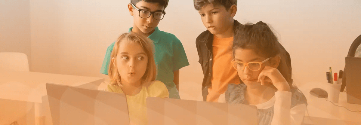 Children working on computers in classroom. Light orange filter on top of image.